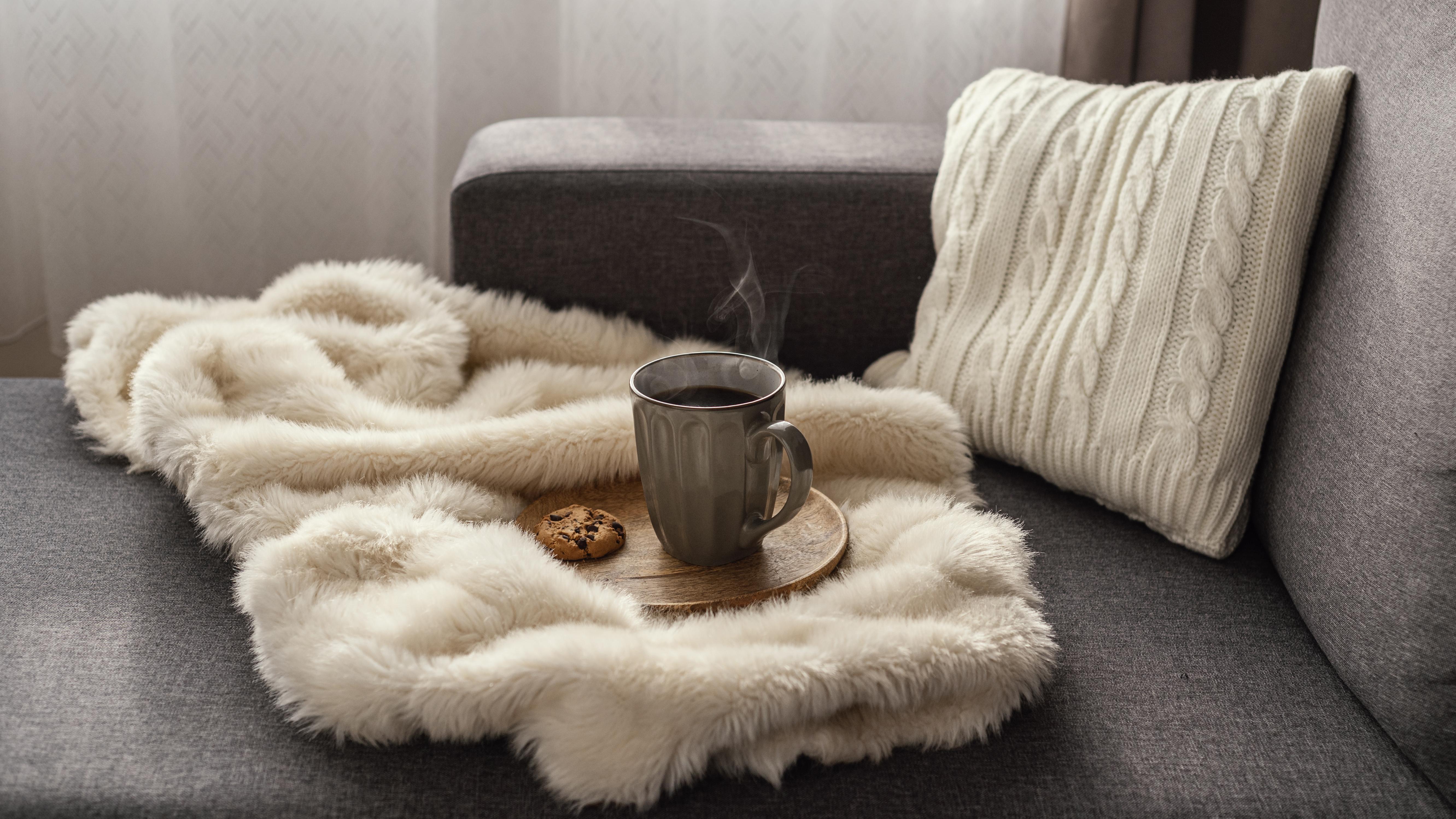 A cozy cottagecore style living room featuring layered Irish wool throws and Donegal tweed cushion covers on a rustic sofa near a window.