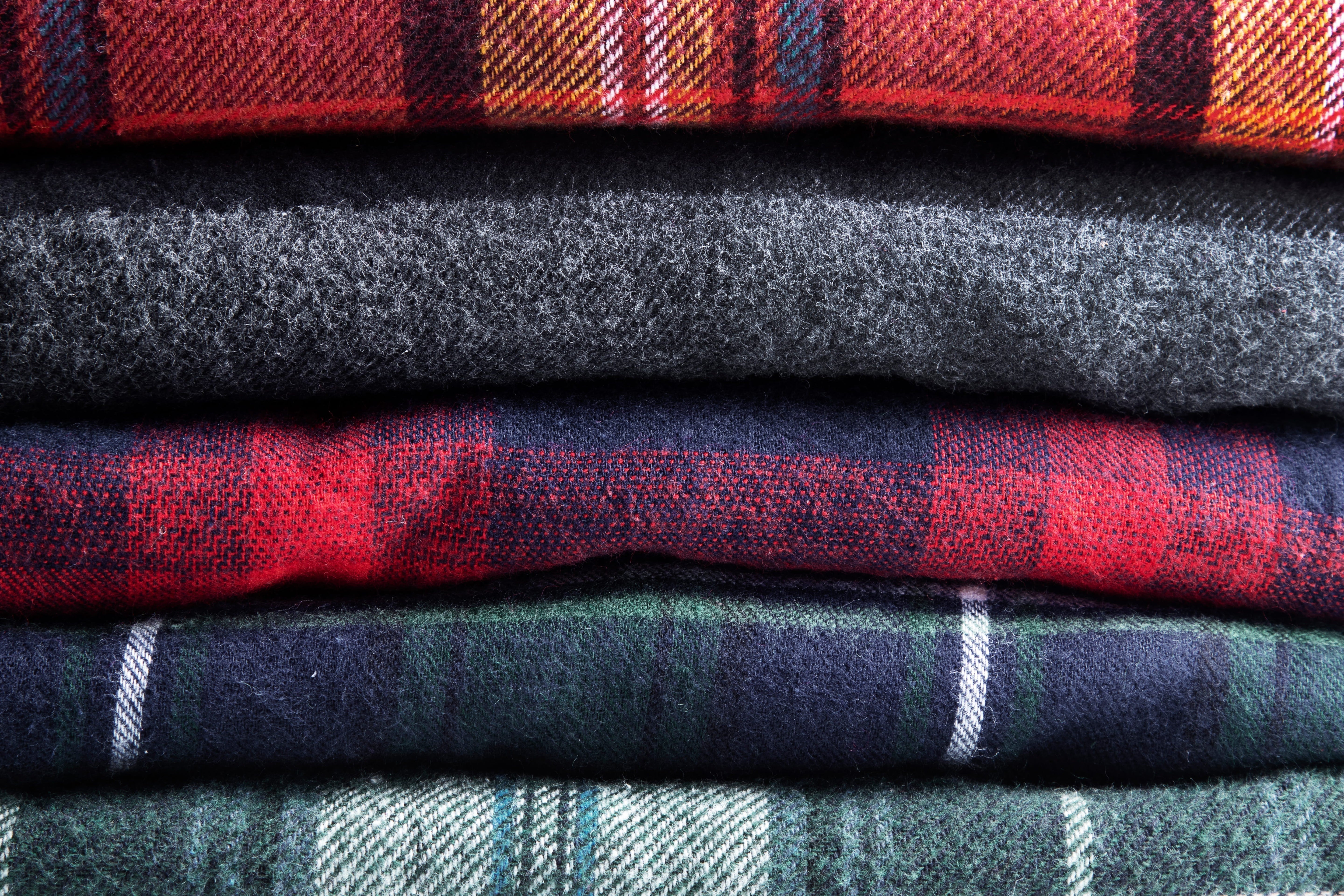 Close-up of natural wool yarns on a traditional wooden loom showing the colorful flecks of authentic Donegal tweed.